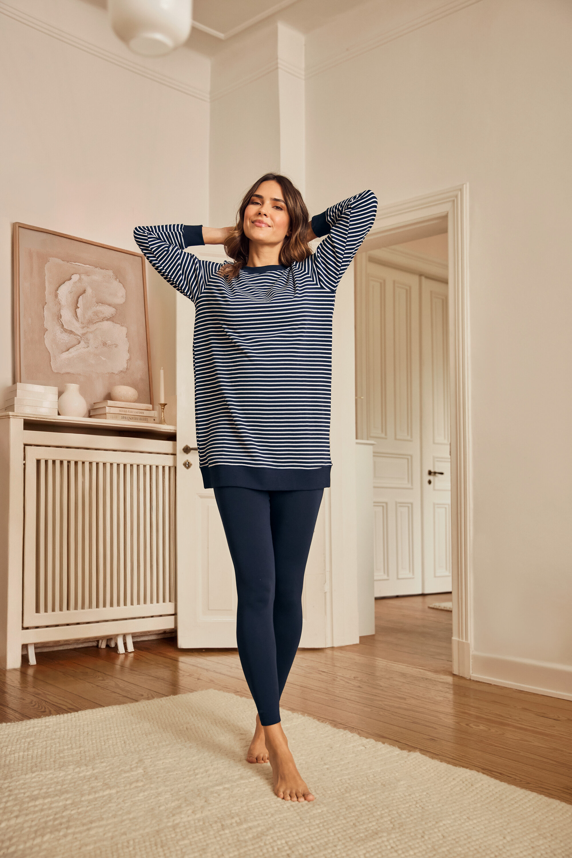 Nő leggings pizsamában áll mezítláb egy szőnyegen.