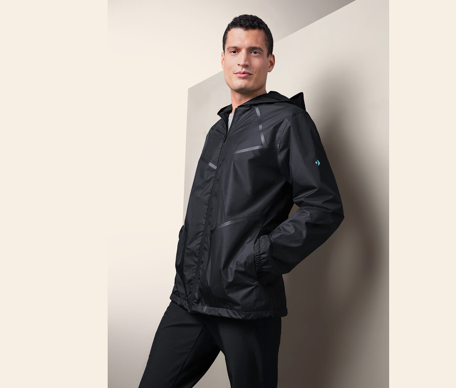 Férfi pózol fekete, minden időjárásra alkalmas kabátban.