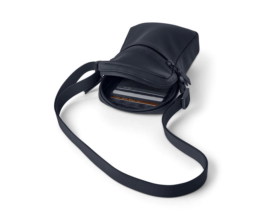 Egy sötétkék vízhatlan oldaltáska pánttal és cipzárral, belül kártyák láthatók.