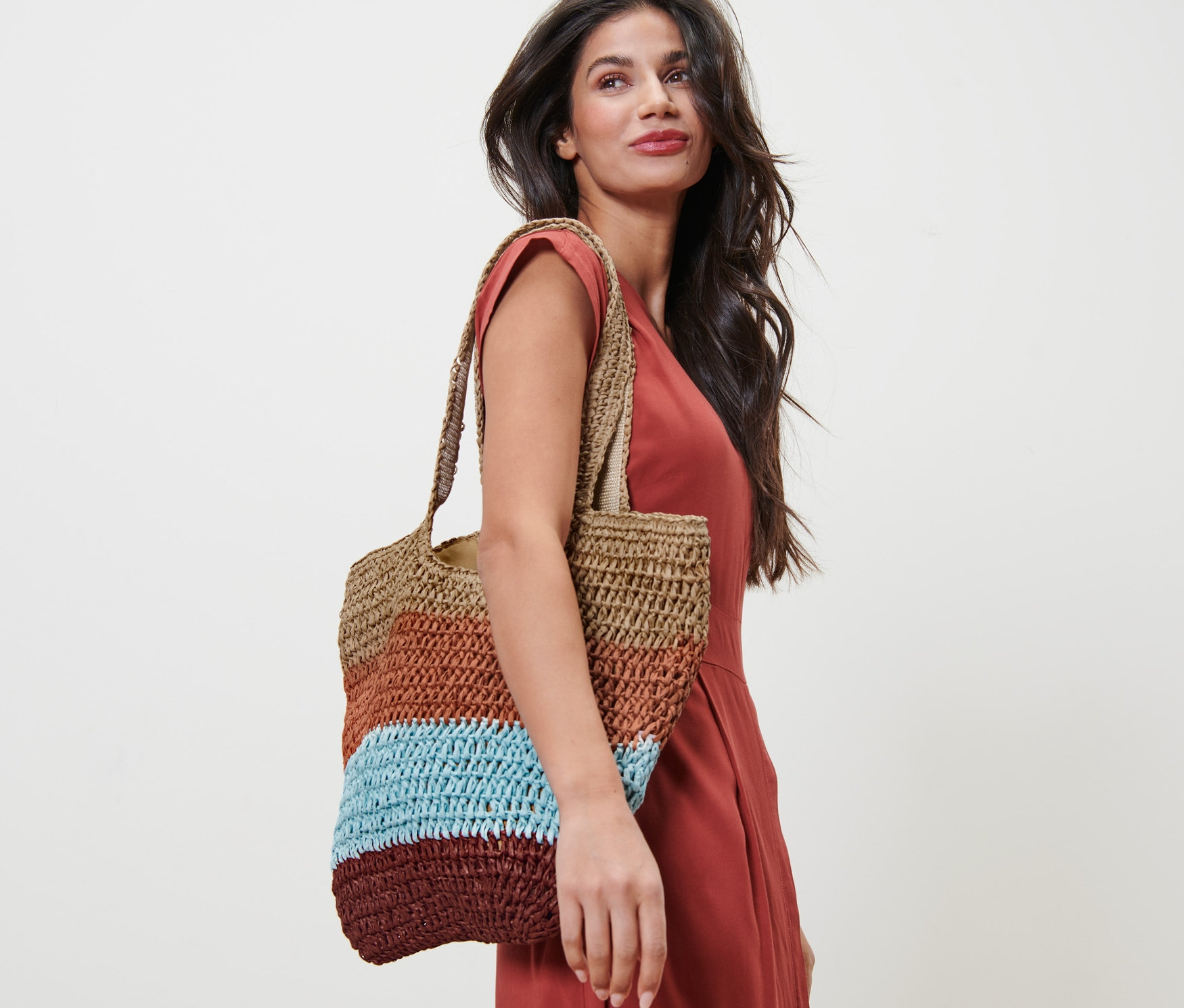 Narancssárga ruhás nő, a vállán egy háncs hatású női shopper táska.