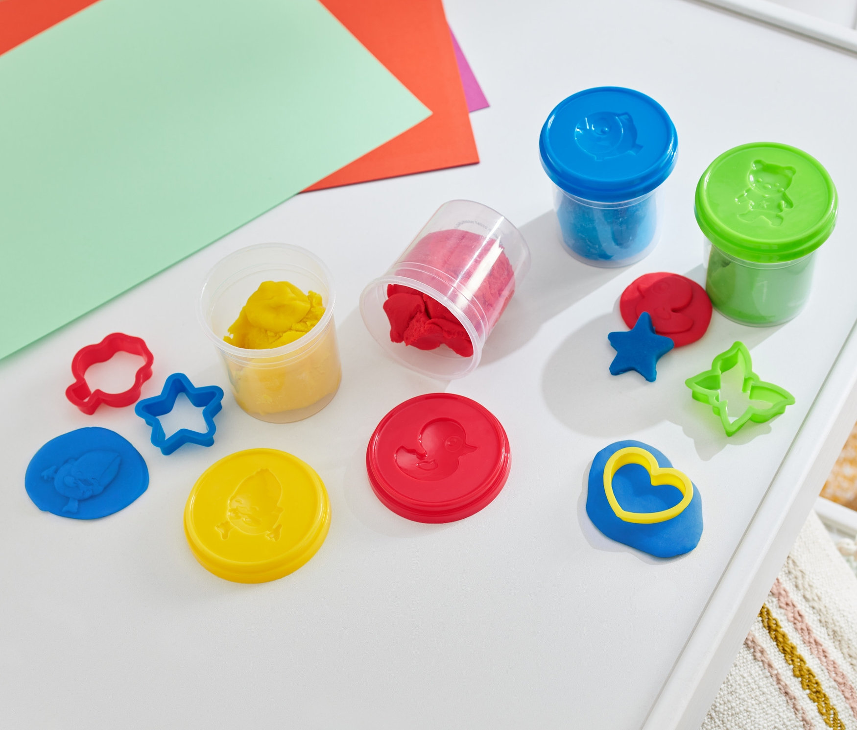 Gyurmaszett egy fehér asztalon, színes papírokkal.