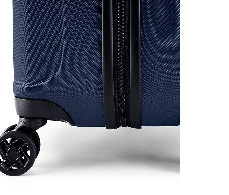 Egy kék, keményfedeles bőrönd részlete cipzárral és kerekekkel.