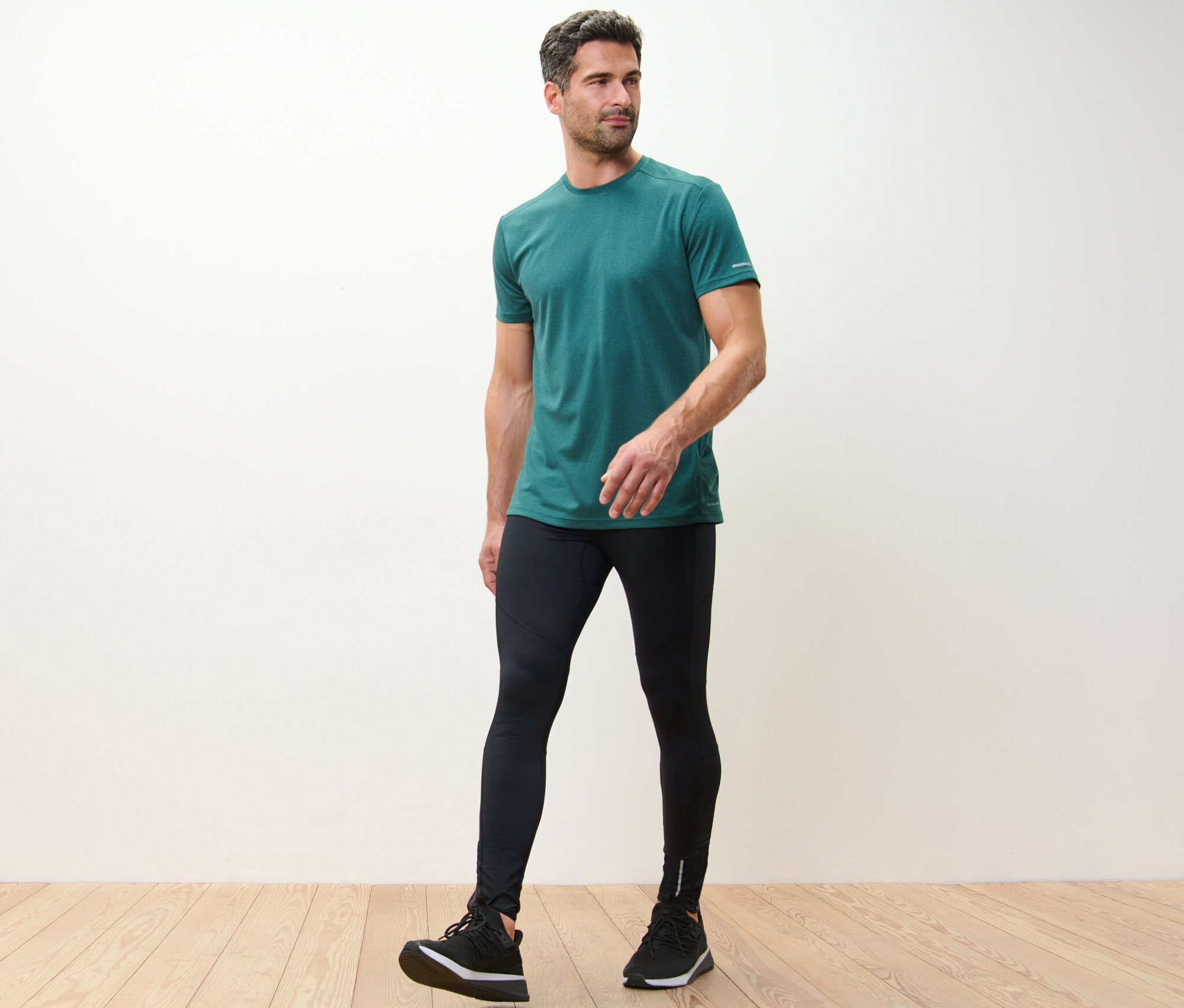 Férfi zöld pólóban és fekete futónadrágban.