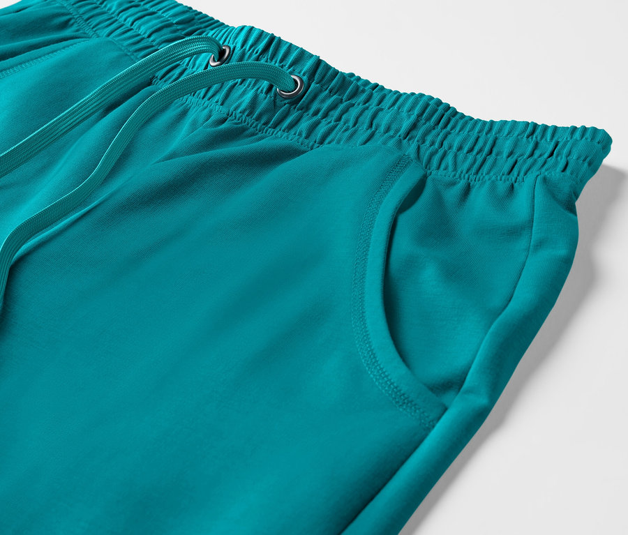 Egy türkiz 3/4-es melegítőnadrág részlete elasztikus derékpánttal és húzózsinórral.