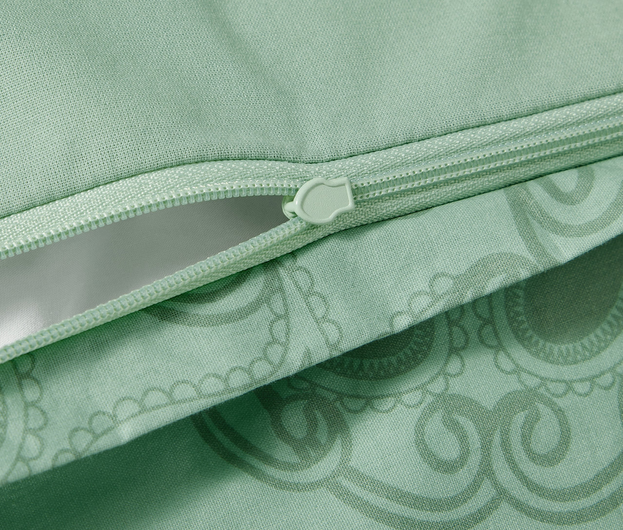 Egy zöld, mandalás, renforcé ágynemű részlete cipzárral.