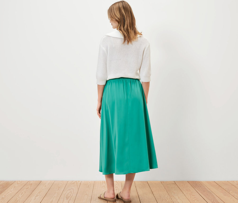 Hátulról álló nő szaténszoknyát visel.