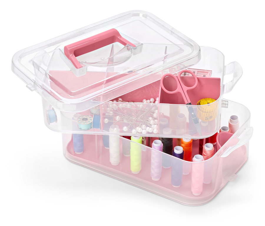 Többszintes, átlátszó műanyag szerszámosláda rózsaszín elemekkel, tele varrókellékekkel.