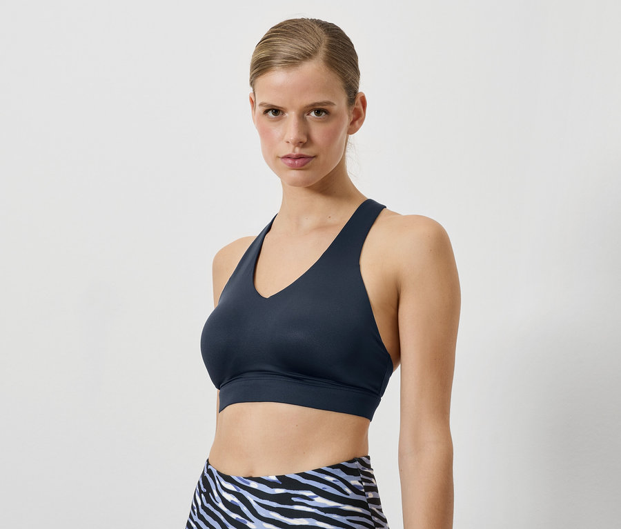 Nő visel sötétkék sportmelltartót és állatmintás leggingset.