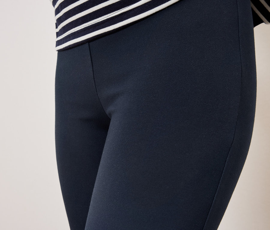 Női sötétkék leggings és egy csíkos felső részletfotója.