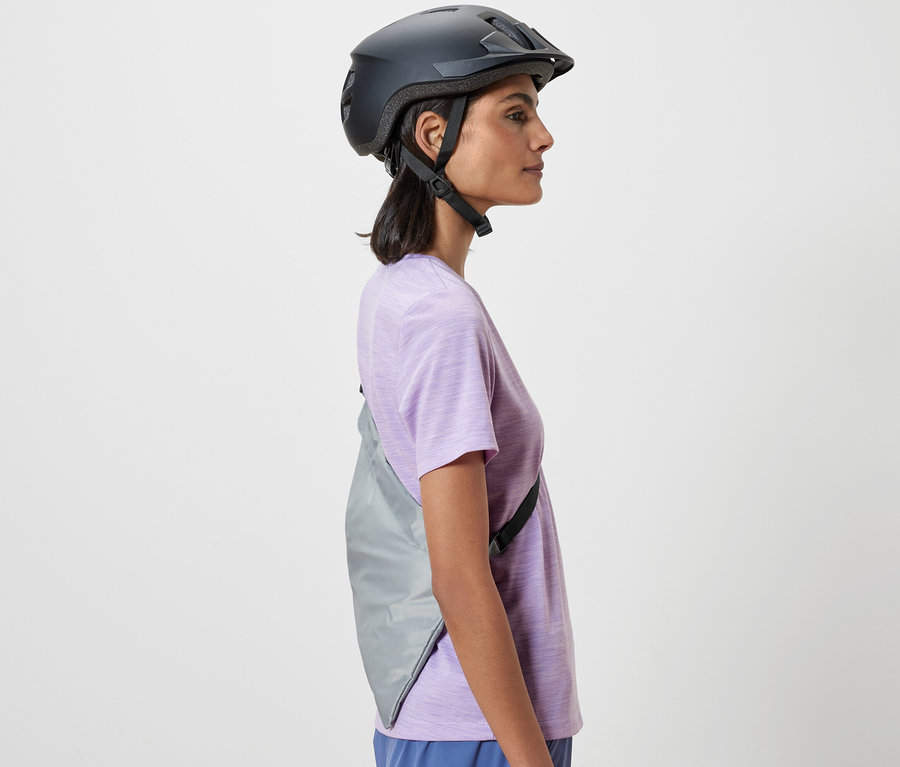 Egy nő oldalnézete kerékpáros sisakban. A vállán egy kerékpáros bevásárlótáska van.