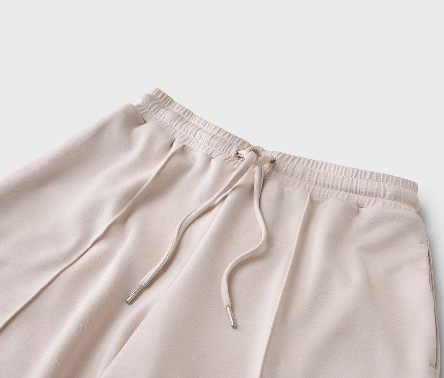 Egy bézs színű, húzózsinóros nadrág közeli képe.