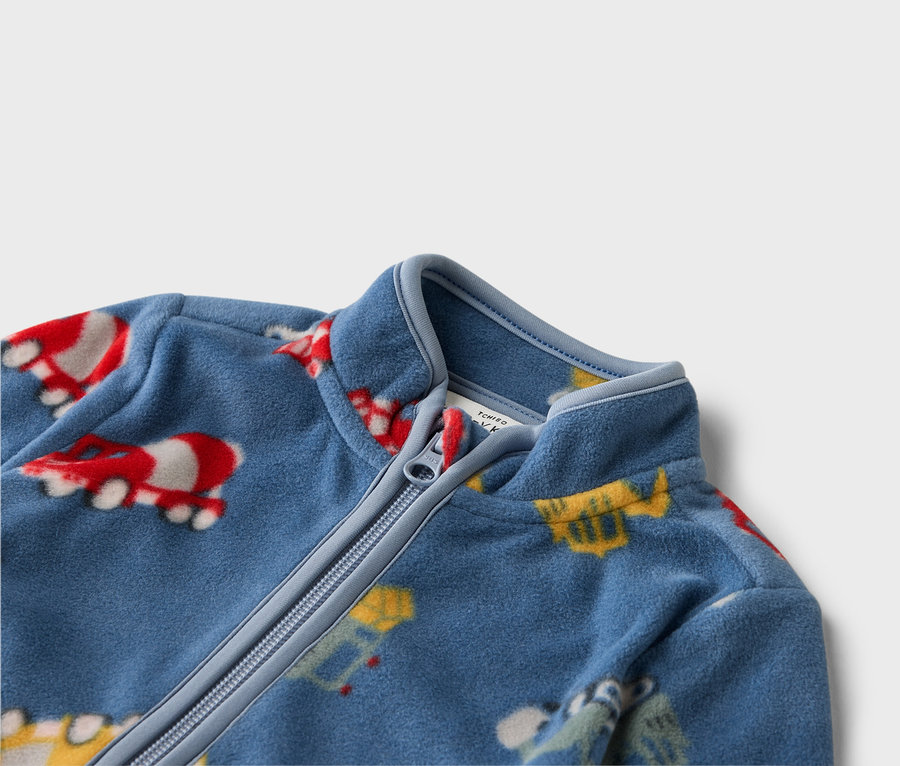 Egy kék, cipzáras, színes járműmintás polár pulóver közelképe.