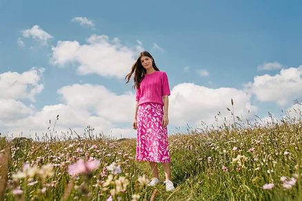 Egy nő áll a mezőn, és bedruckter midi-rock, Női fülbevaló, Wave és Bőr sneaker van rajta.