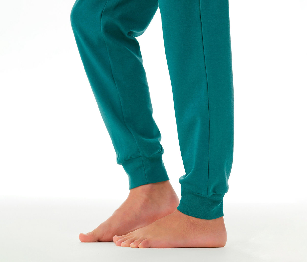 Gyermek mezítlábas lábai és alsó lábszárai türkiz SCHIESSER Kinder-Interlock-Pyjama alsóban, mandzsettával.