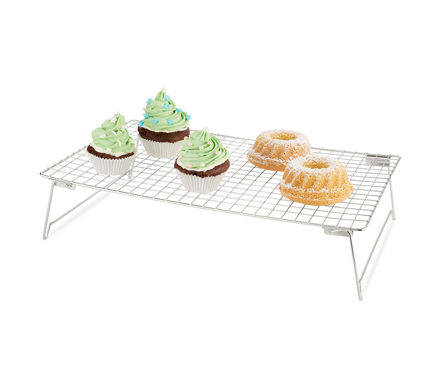 Három zöld díszítésű muffin és két porcukorral meghintett kuglóf a háromszintes hűtőrácson.