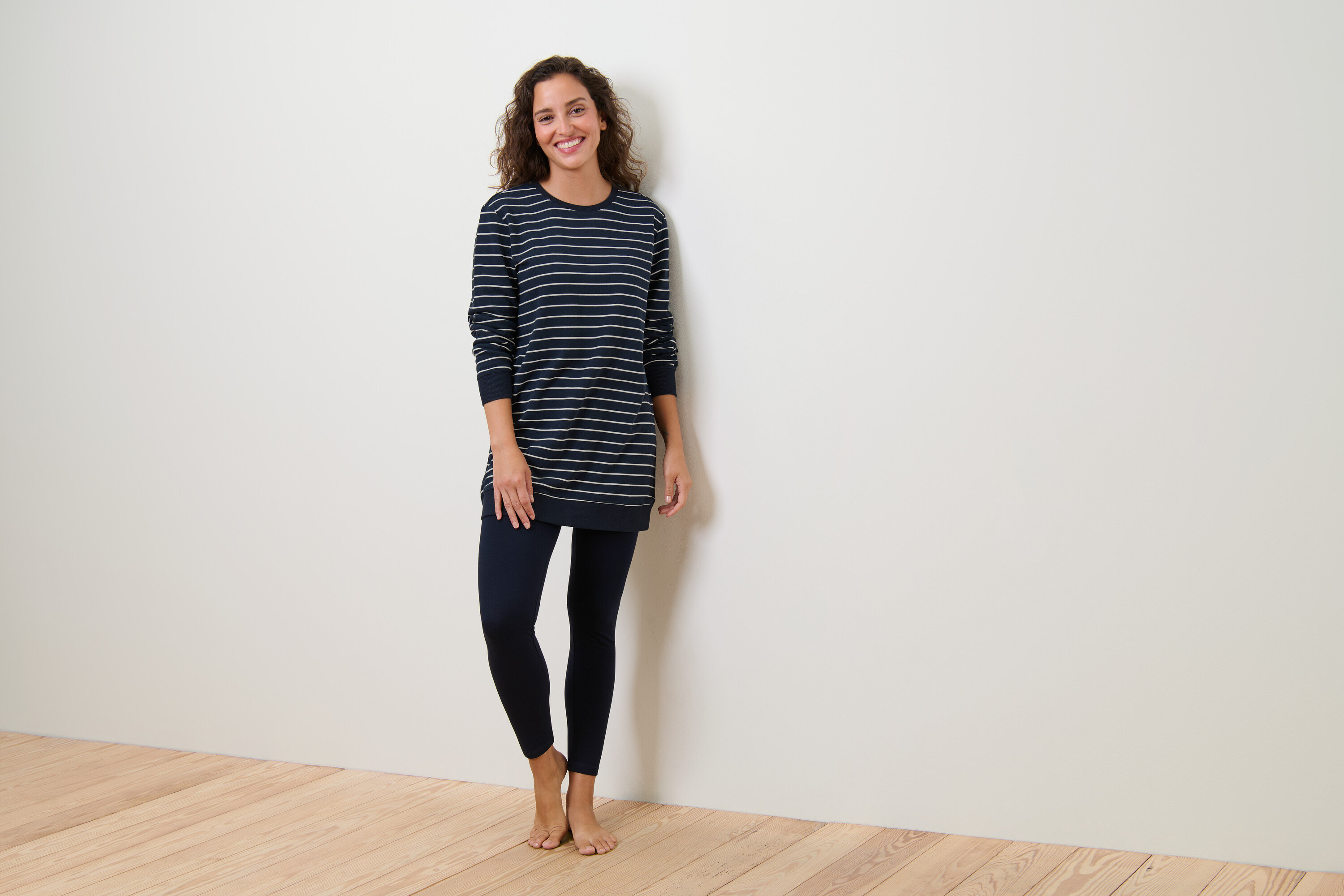 Nő visel csíkos, sötétkék leggingszel ellátott pizsamát.