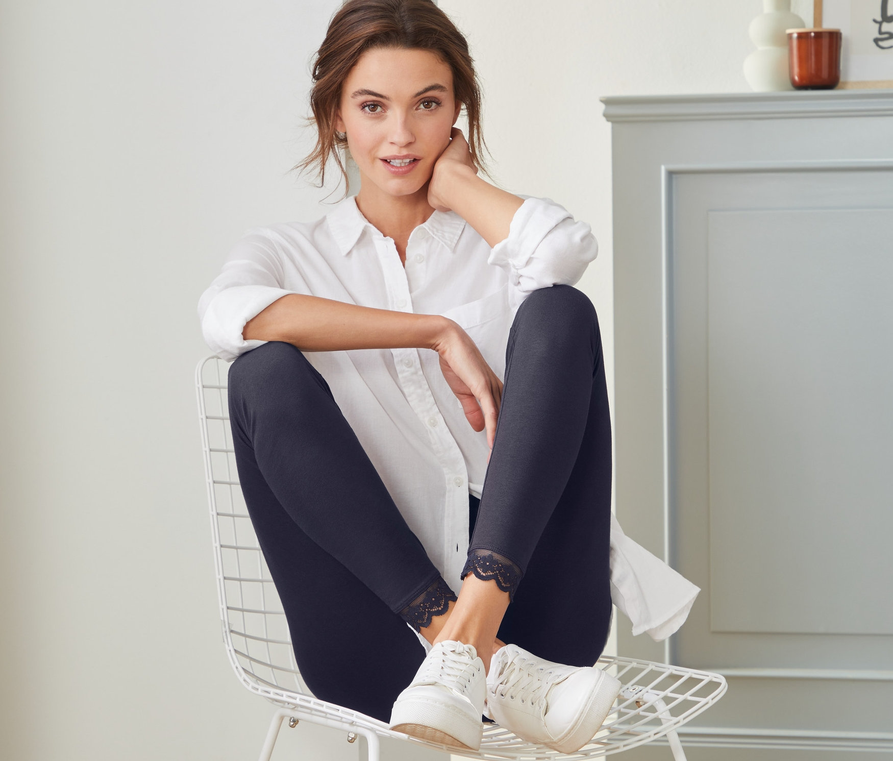 Nő ül egy széken, és csipkés szegélyű leggingset visel.