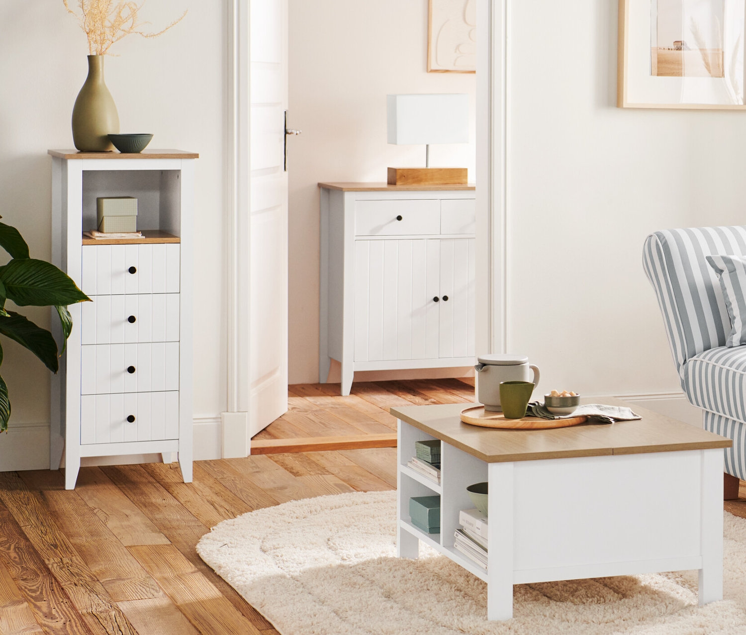 A nappaliban egy fa állólámpa »Trojnožka« áll egy kanapé és egy dohányzóasztal felhajtható asztallappal mellett. A háttérben egy komód fiókokkal látható.