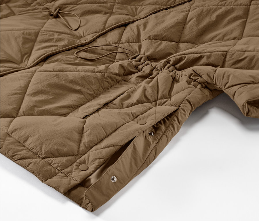 Egy barna, steppelt női poncsó részlete.