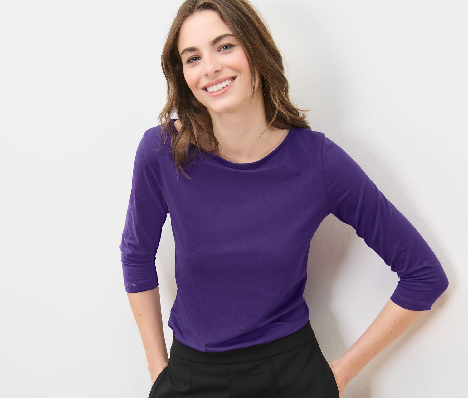 Nő lila, 3/4-es ujjú felsőben pózol.
