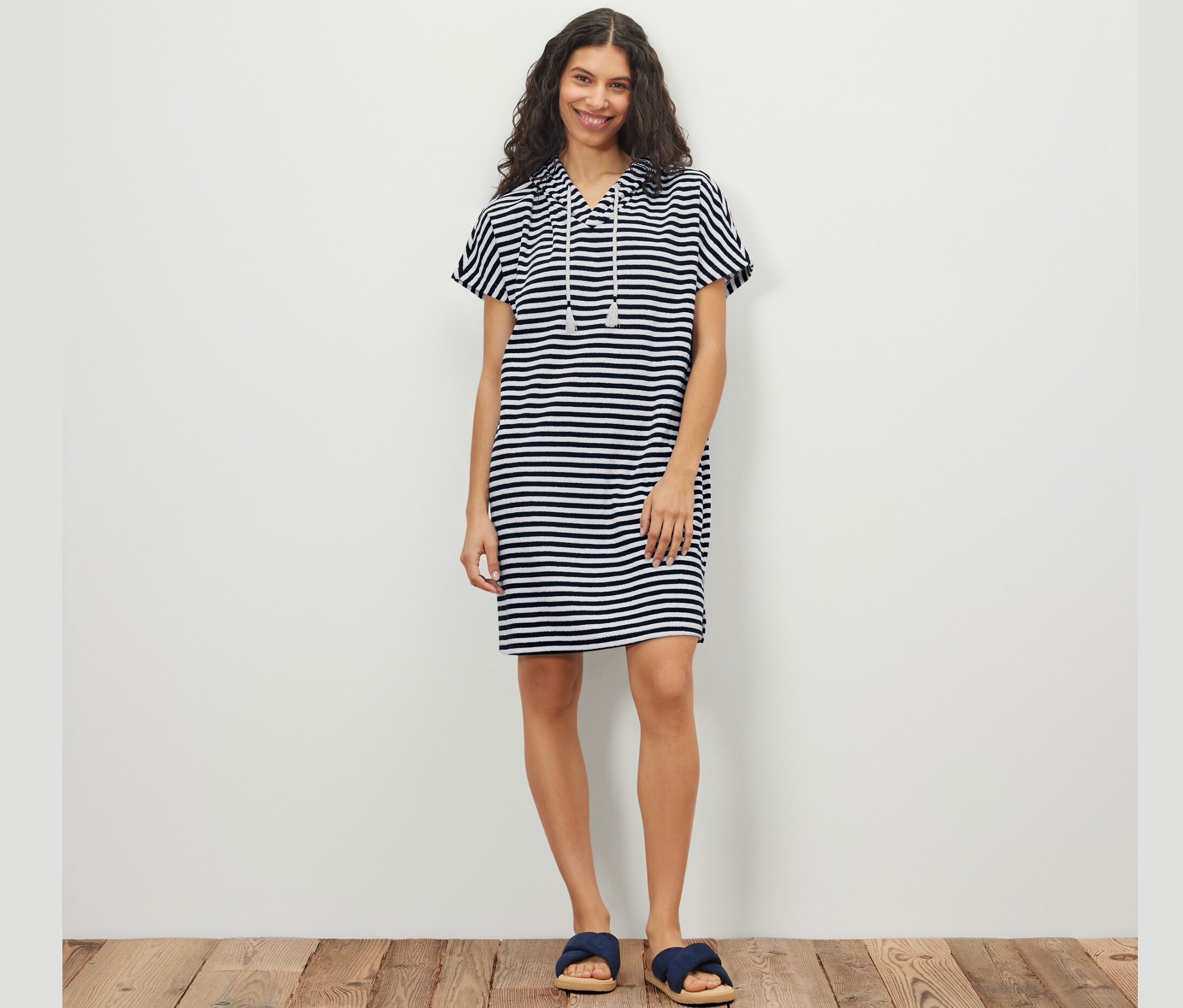 Nő pózol csíkos frottír strandruhában.