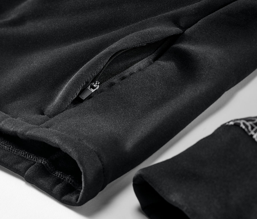 Egy fekete termodzseki részlete cipzáras zsebbel és ujjvéggel.