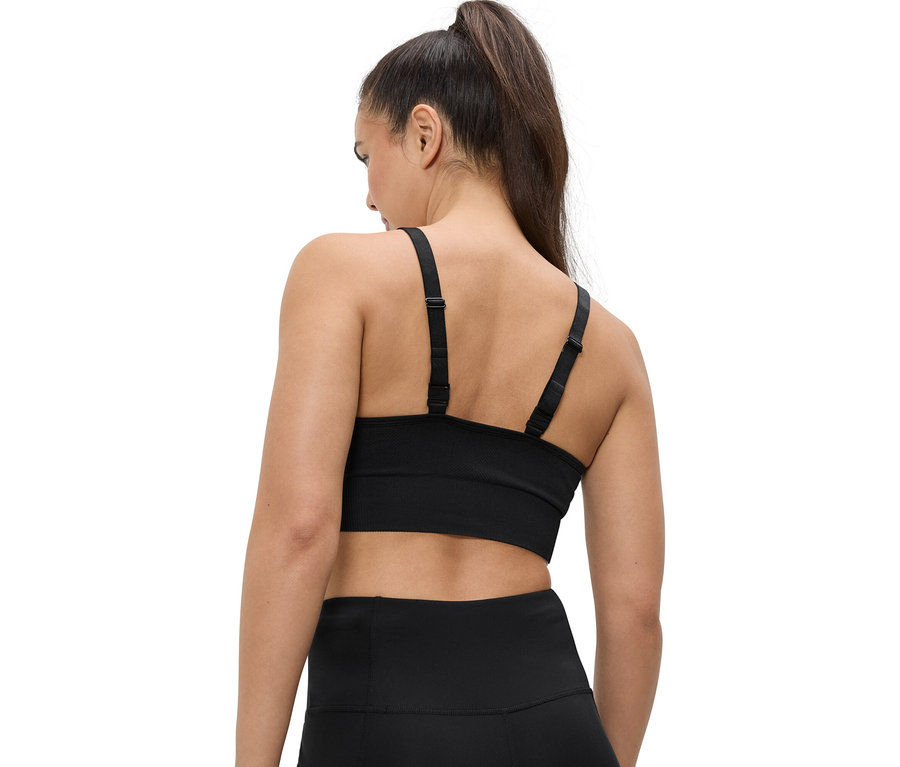Hátulnézet egy lófarokba kötött hajú nőről, aki fekete sportmelltartót és leggingset visel.