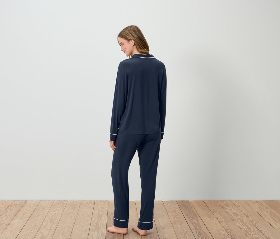 Hátulról látható nő sötétkék, fehér szegélyű pizsamában.