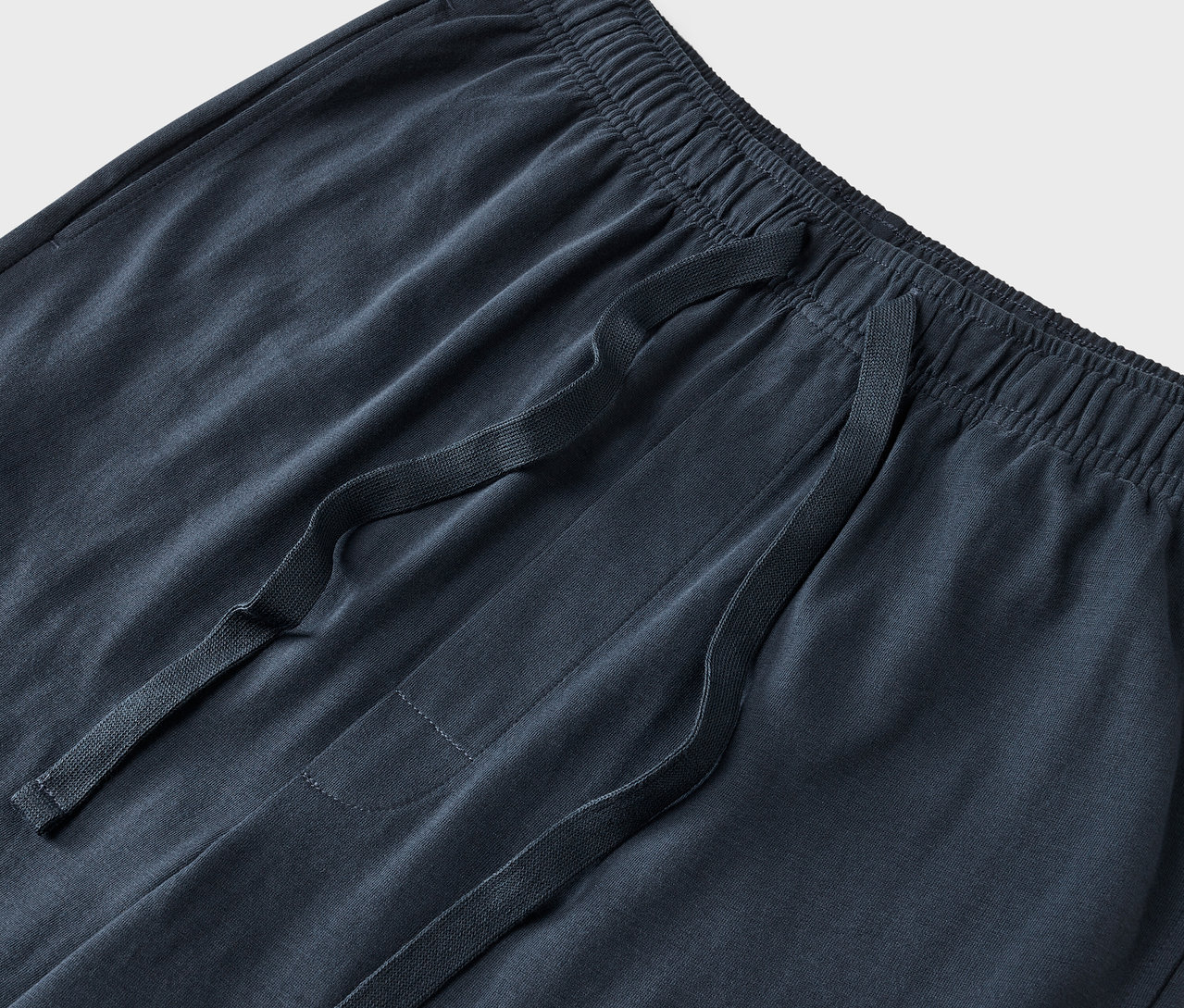 Egy sötétkék színű szabadidőnadrág részlete, húzózsinórral a derékrészen.