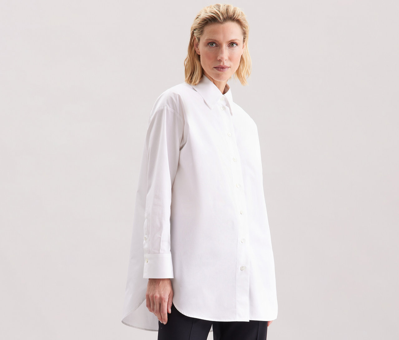 Nő visel egy fehér Seidensticker túlméretes hosszú ingblúzt.