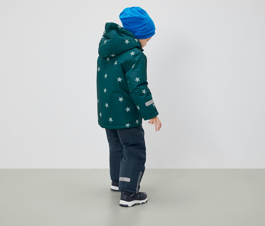 A hátulról látható fiú csillagmintás télikabátot, kék sapkát és sötétkék nadrágot visel.