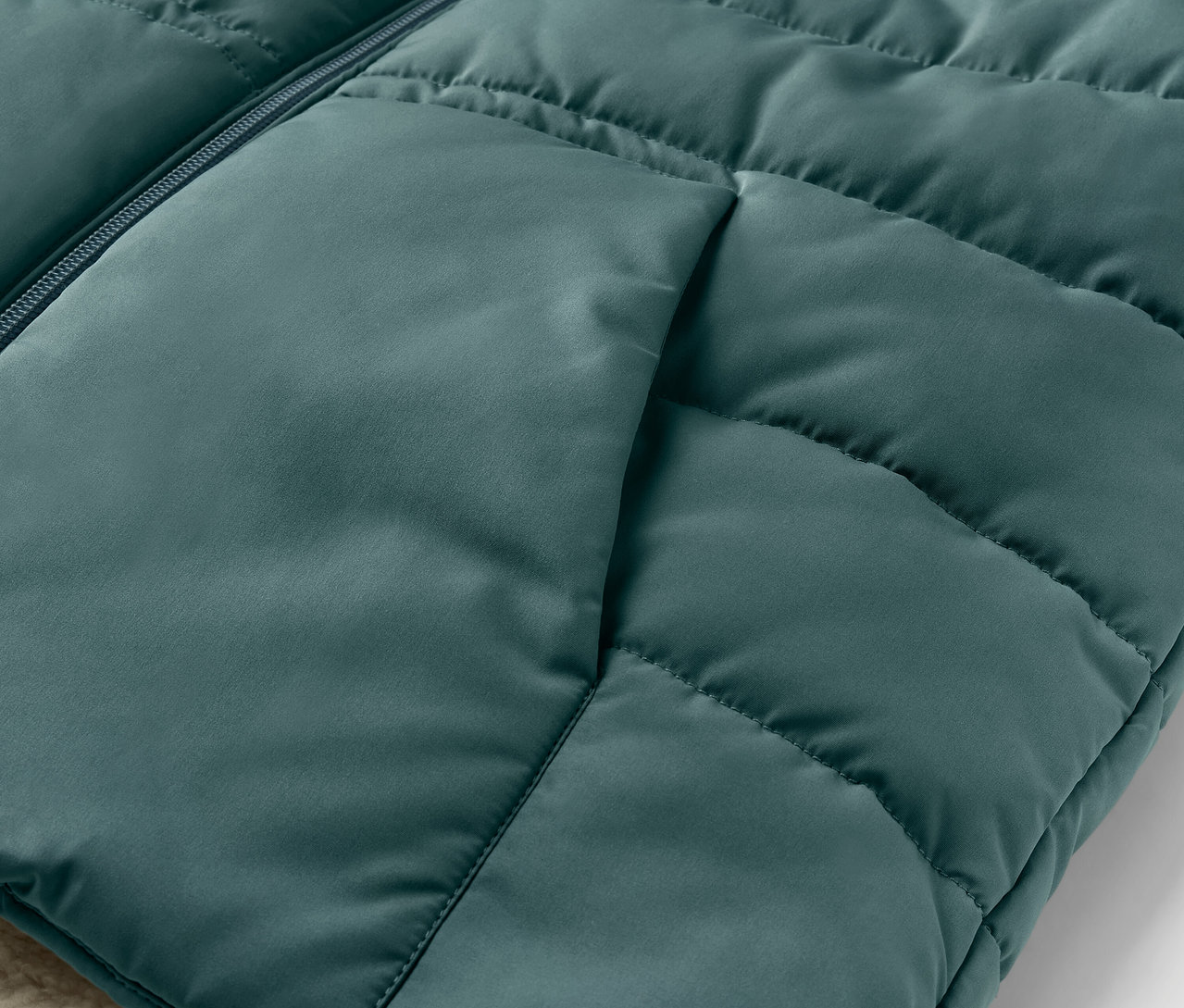 Egy plüss, steppelt gyerekmellény részlete zsebbel.