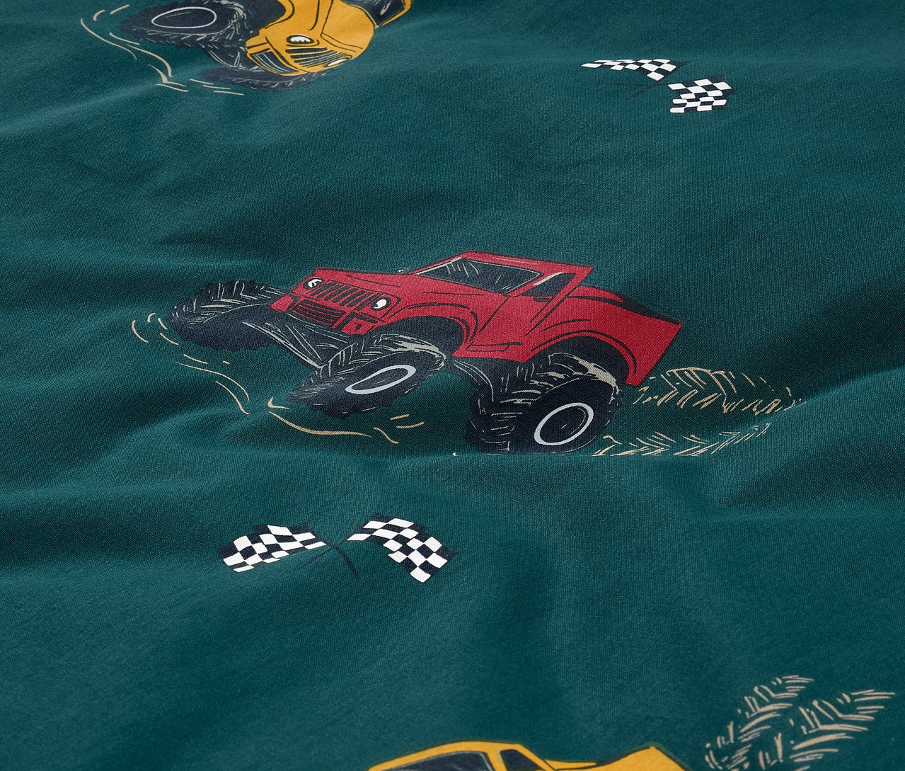 Közelkép egy normál méretű, kamion mintás Kinder-Renforcé ágyneműhuzatról.