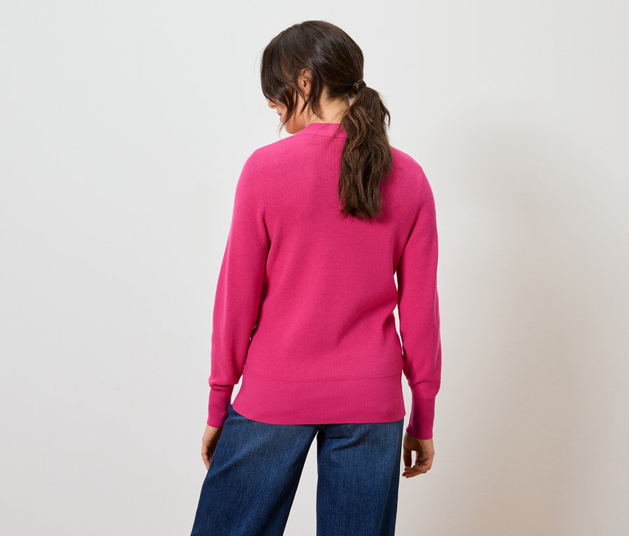 Hátulról látható egy nő rózsaszín pulóverben és kék farmerben.