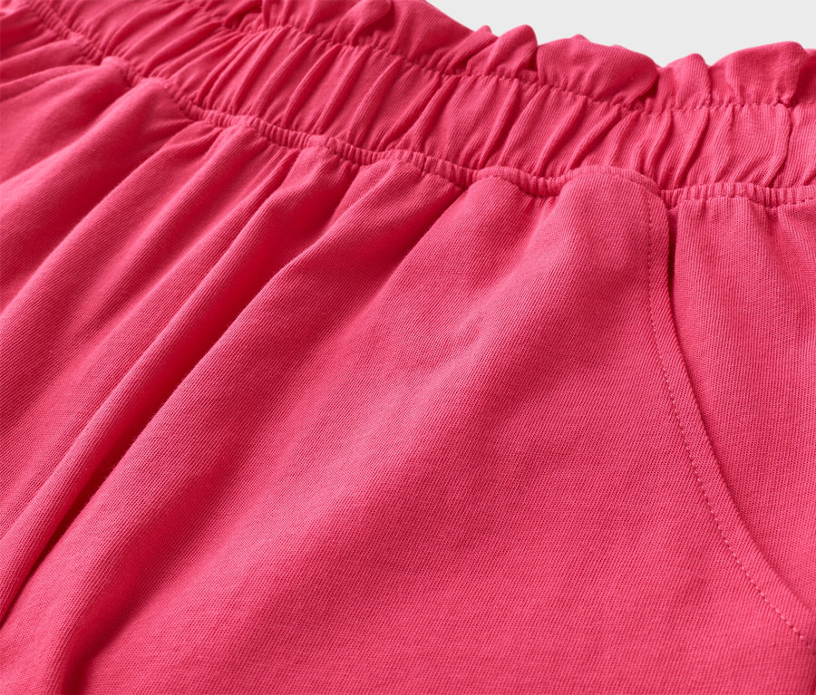 Közelkép egy rózsaszín rövidnadrágról, gumis derékrésszel és zsebbel.