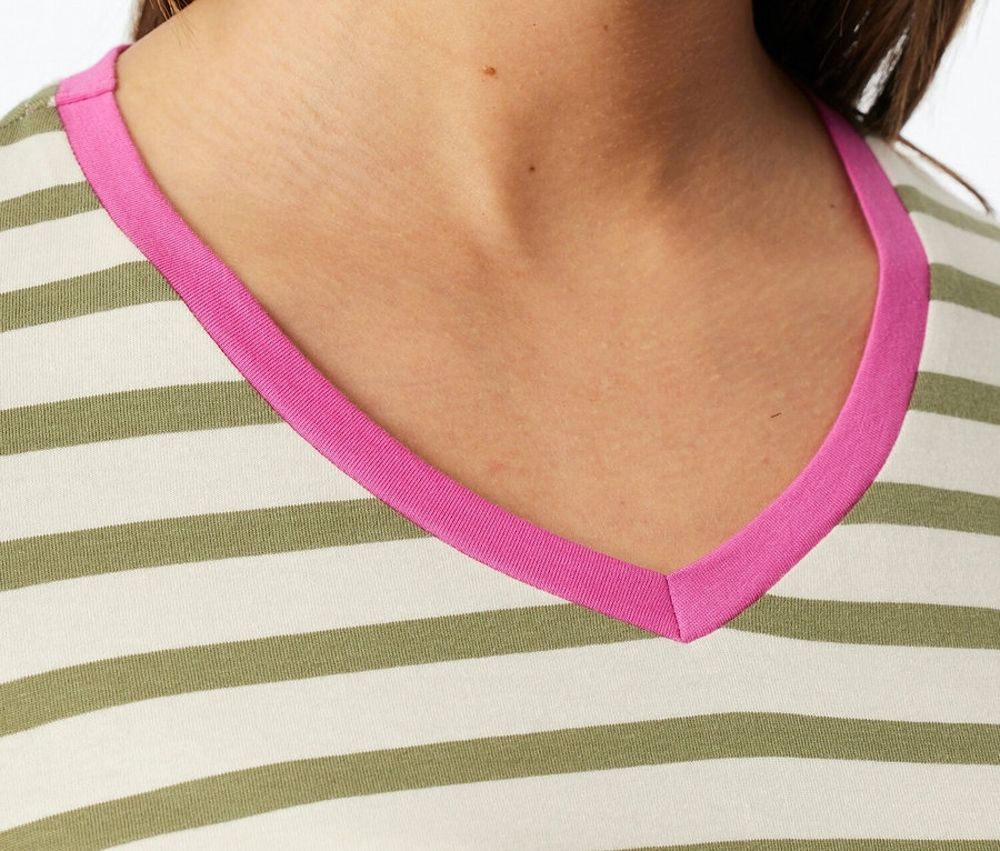 Közeli kép egy csíkos felsőt viselő nőről, rózsaszín V-nyakkal.