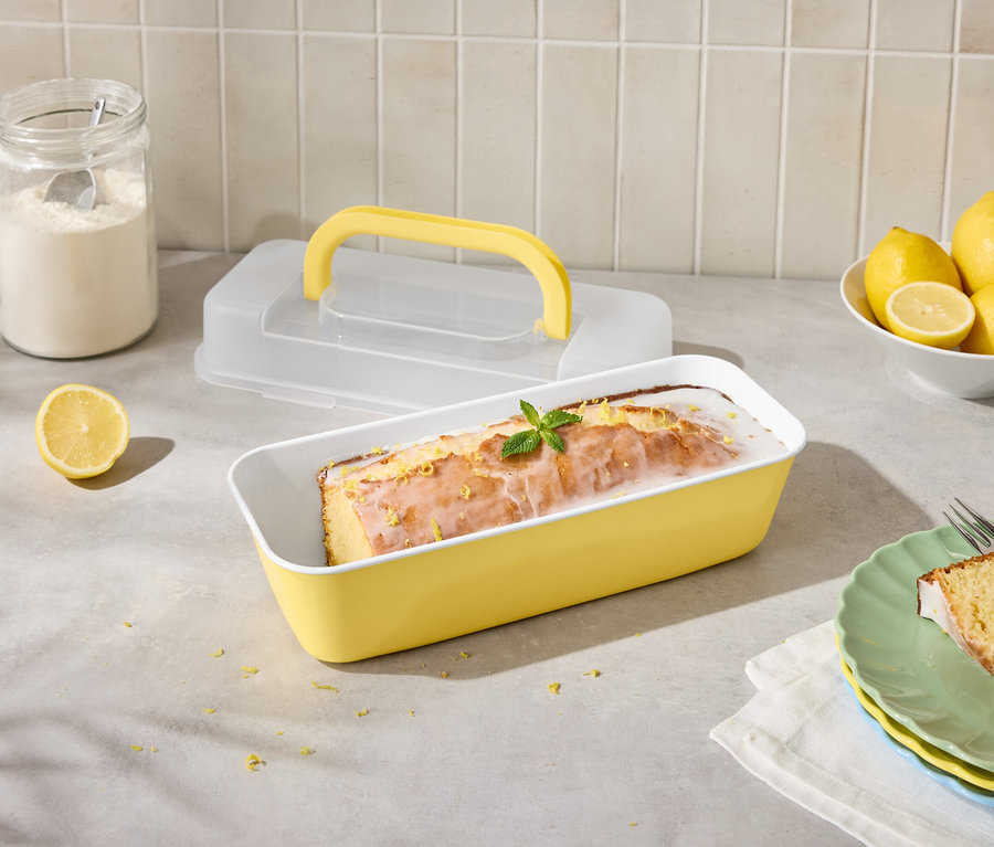 Citromos sütemény sárga formában, citromokkal és cukormázzal, szeletelve tányéron villával.