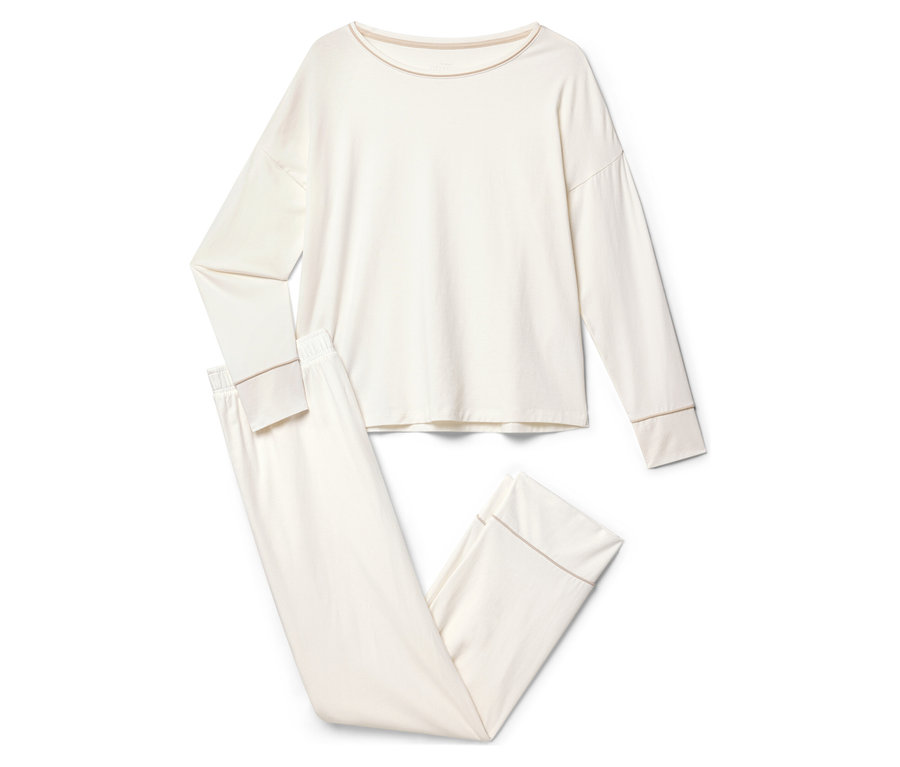 Egy krémszínű, hosszú ujjú és nadrágos pizsama fekszik egy fehér háttéren.