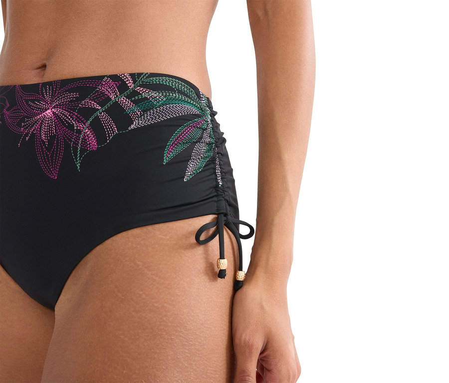 Közeli kép egy virágmintás fekete bikinialsót viselő nőről.