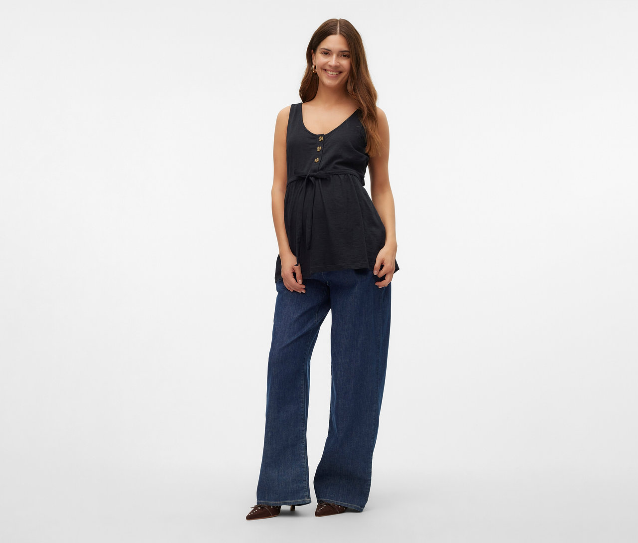 Nő visel gombos és megkötős MAMALICIOUS szoptatós top »MLEVI LIA«-t, farmert és cipőt.