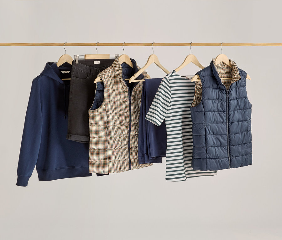 Ruhák lógnak egy fa rúdon, köztük egy zöld csíkos, félhosszú ujjú felső.