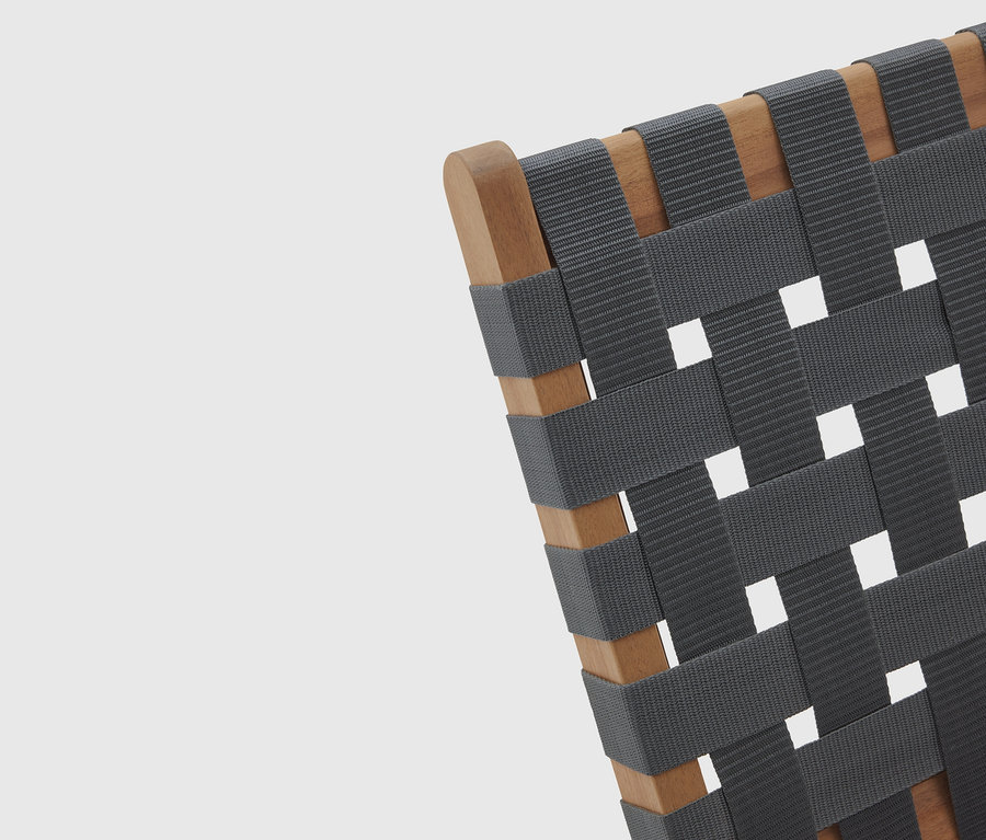 Egy fa vázú, szőtt, szürke ülőfelületű szék részletfotója.