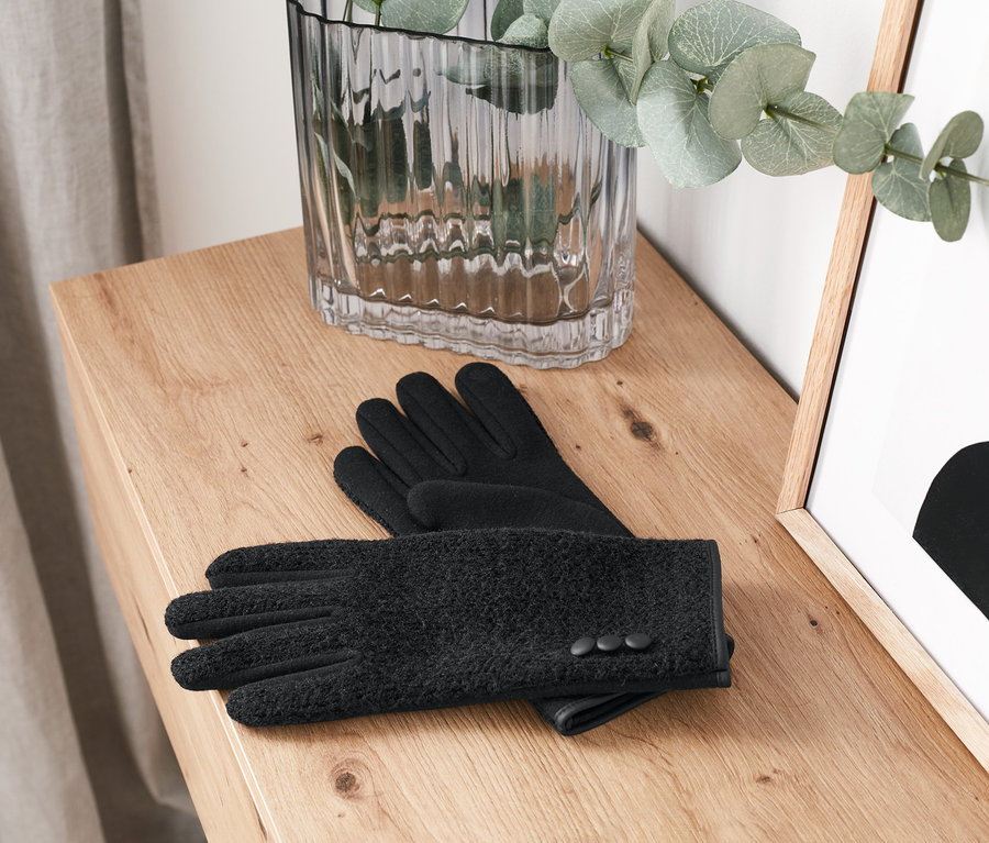 A fa komódon egy fekete női kesztyű fekszik.