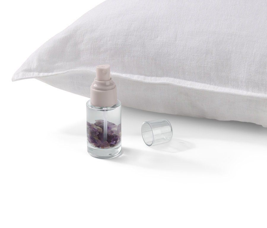 Egy ametiszt spray egy fehér párna mellett áll.