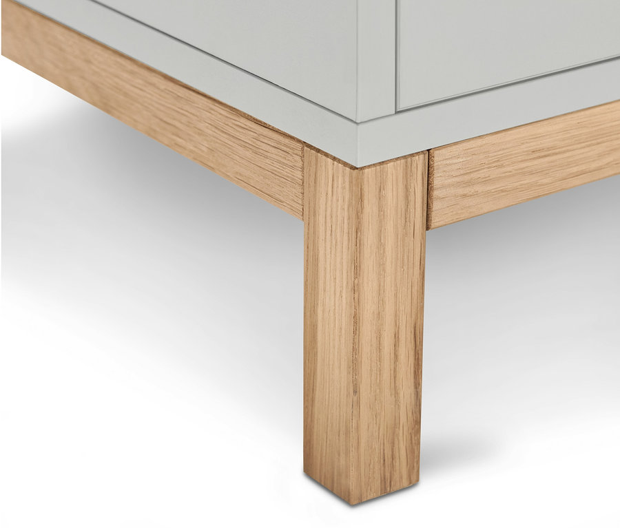 A világosszürke, kétfiókos Eklund mosdó alatti szekrény alsó részének részlete világos fa lábakkal.