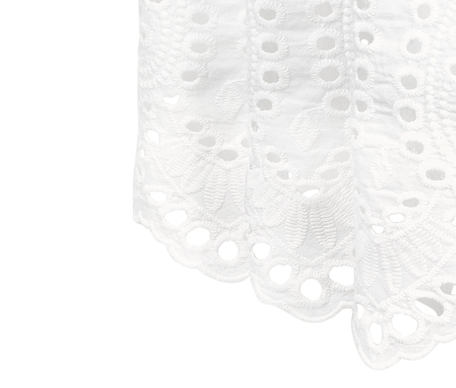 Egy fehér, lyukhímzéses női szoknya részlete.