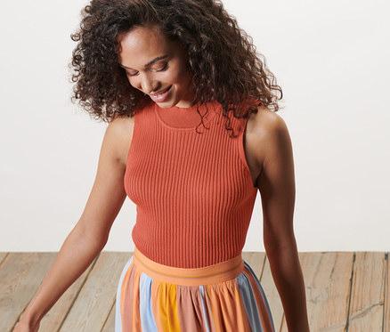 Nő kötött felsőben és csíkos szoknyában lefelé néz.