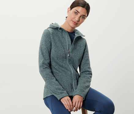 Nő ül egy széken, melírozott menta színű kötött polárfelsőt visel.