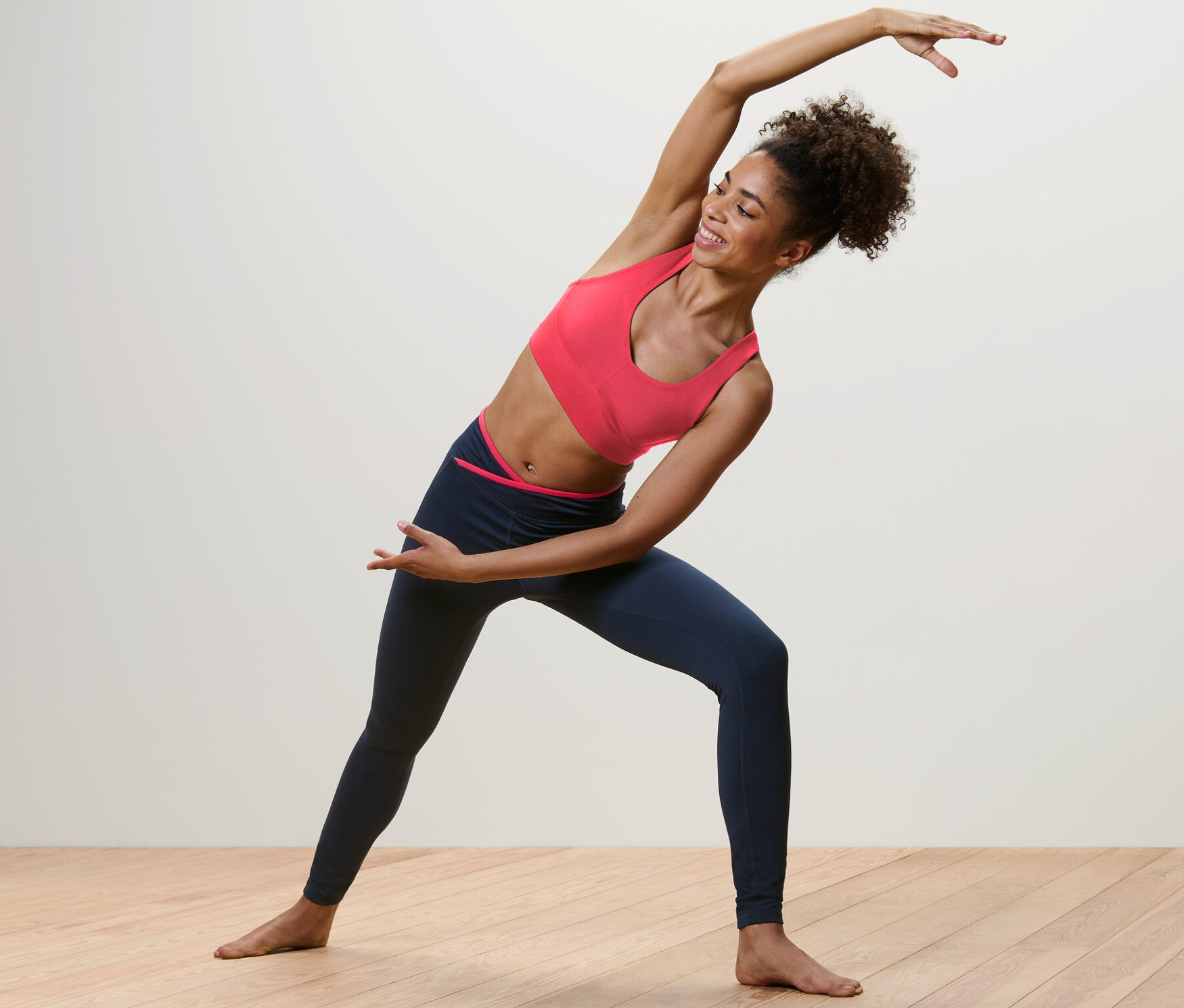 Nő nyújtózkodik sötétkék/pink színű női sportnadrágban.