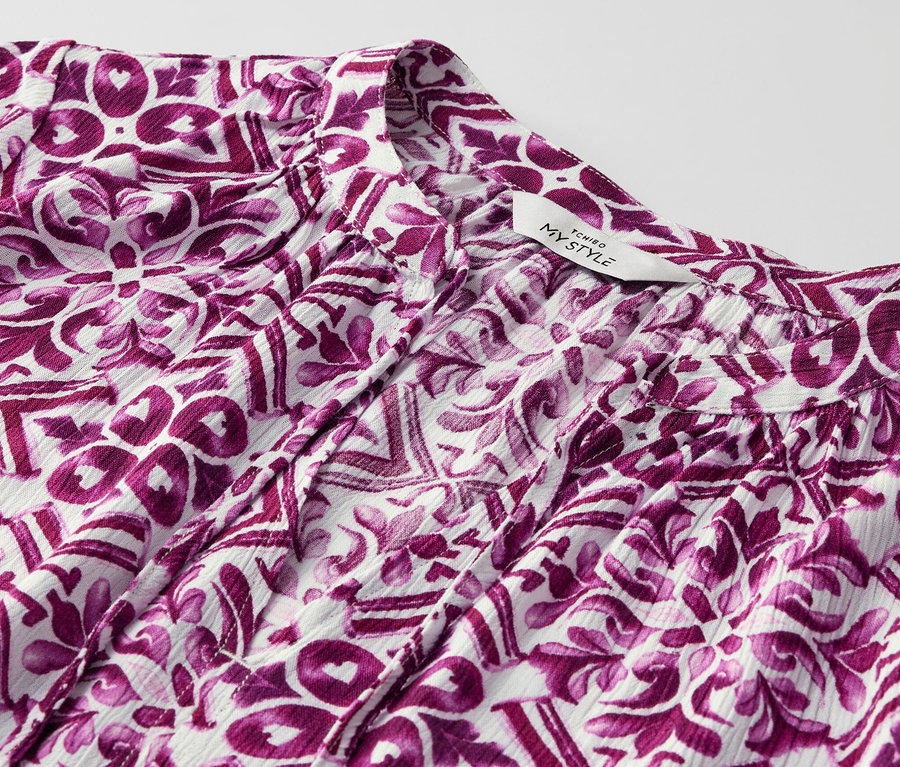 Egy mintás, fukszia színű női tunikablúz részlete.